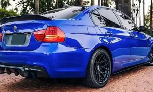 Niebieskie BMW E90 z czarnym spoilerem na klapie bagażnika i dyfuzorem.