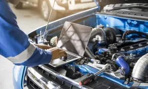Mechanik z laptopem przy silniku samochodu.