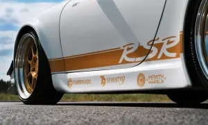 Biały samochód z pomarańczowymi naklejkami "RSR", "CARBONADO", "SEVENTY9" i "WRATH WHEELS".
