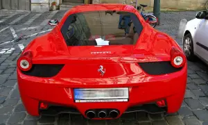 Czerwone Ferrari z widocznym logo konia, na brukowanej ulicy.
