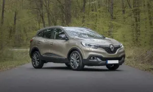 Złoty SUV stoi na drodze w lesie z zielonymi drzewami w tle.