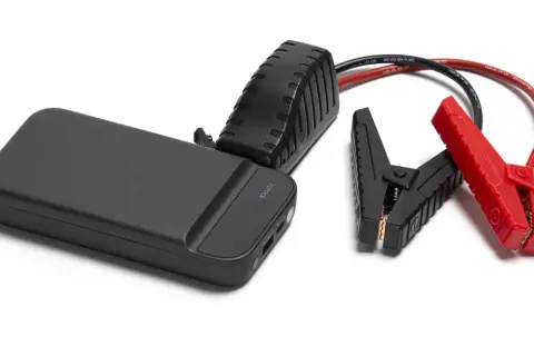 Czarny jump starter z czerwonymi i czarnymi klemami na białym tle.