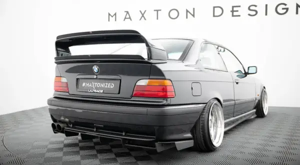 Czarne BMW E36 z tuningowym zderzakiem, dyfuzorem i dużym spoilerem.