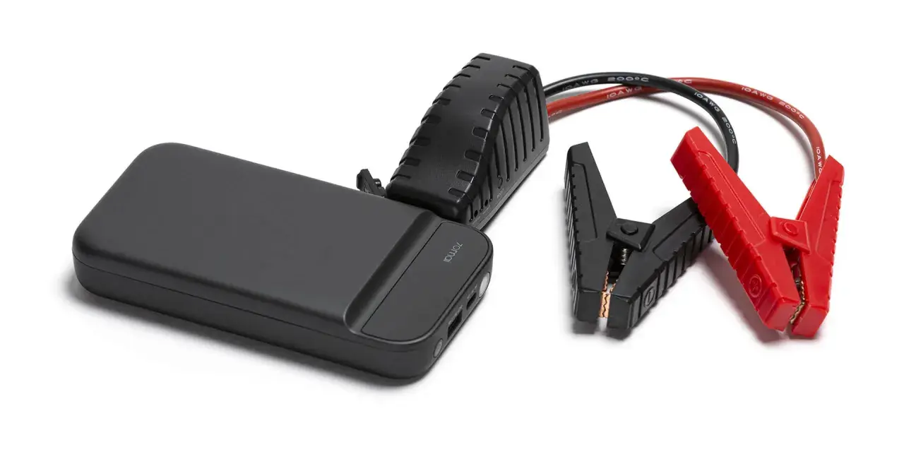 Czarny jump starter z czerwonymi i czarnymi klemami na białym tle.